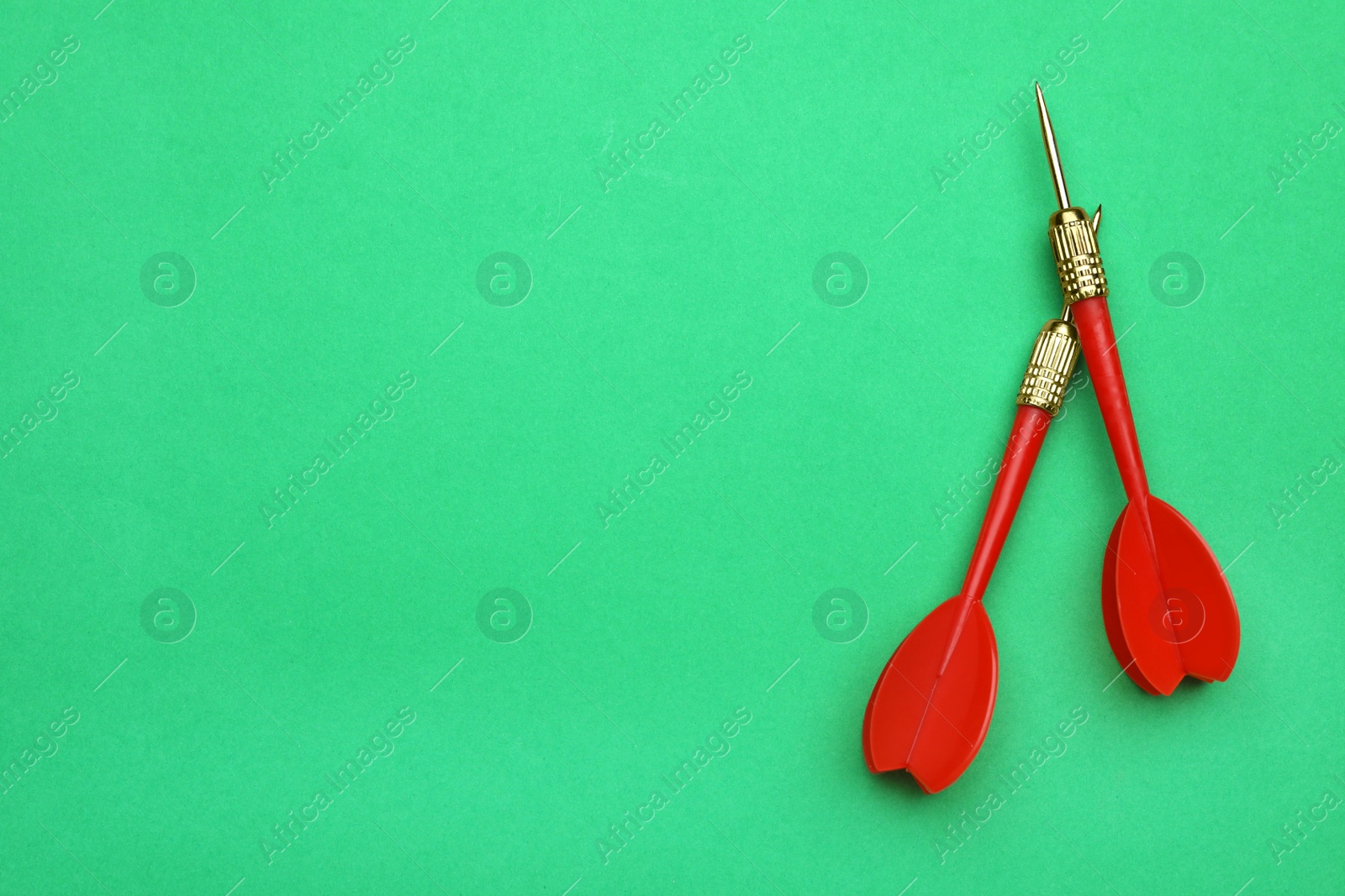 Photo of Red dart arrows on green background, flat lay with space for text