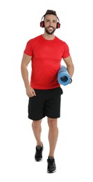 Photo of Handsome man with yoga mat and headphones on white background