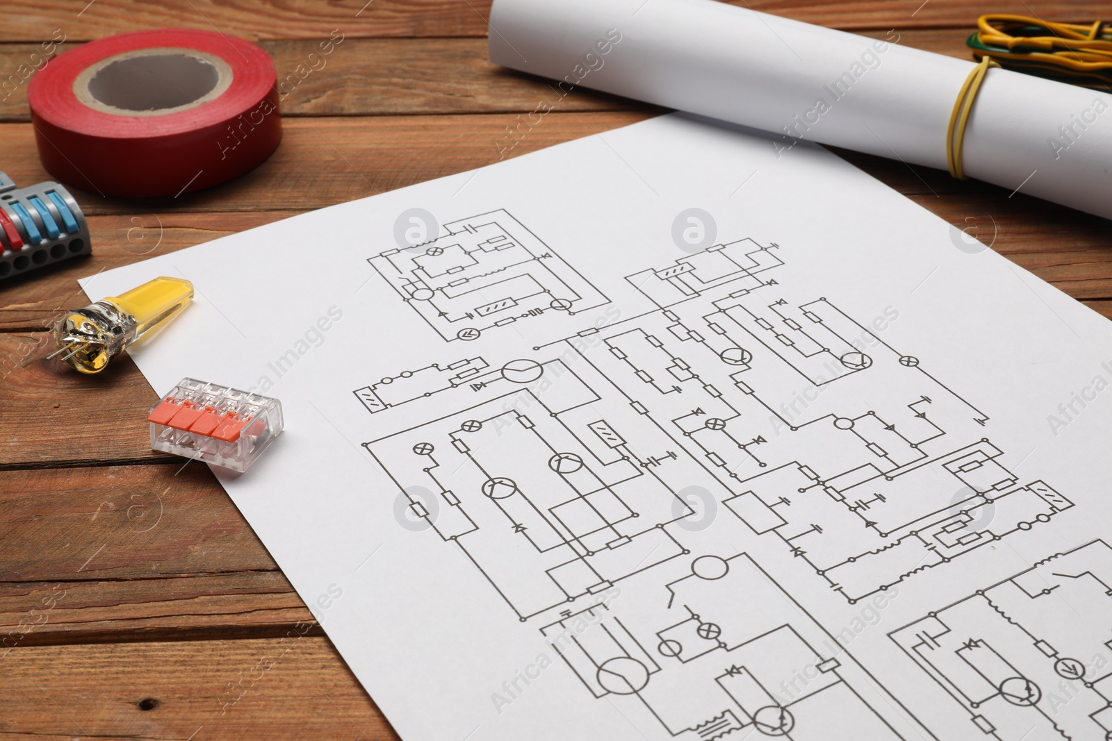 Photo of Wiring diagram, different electrician's equipment and insulating tape on wooden table