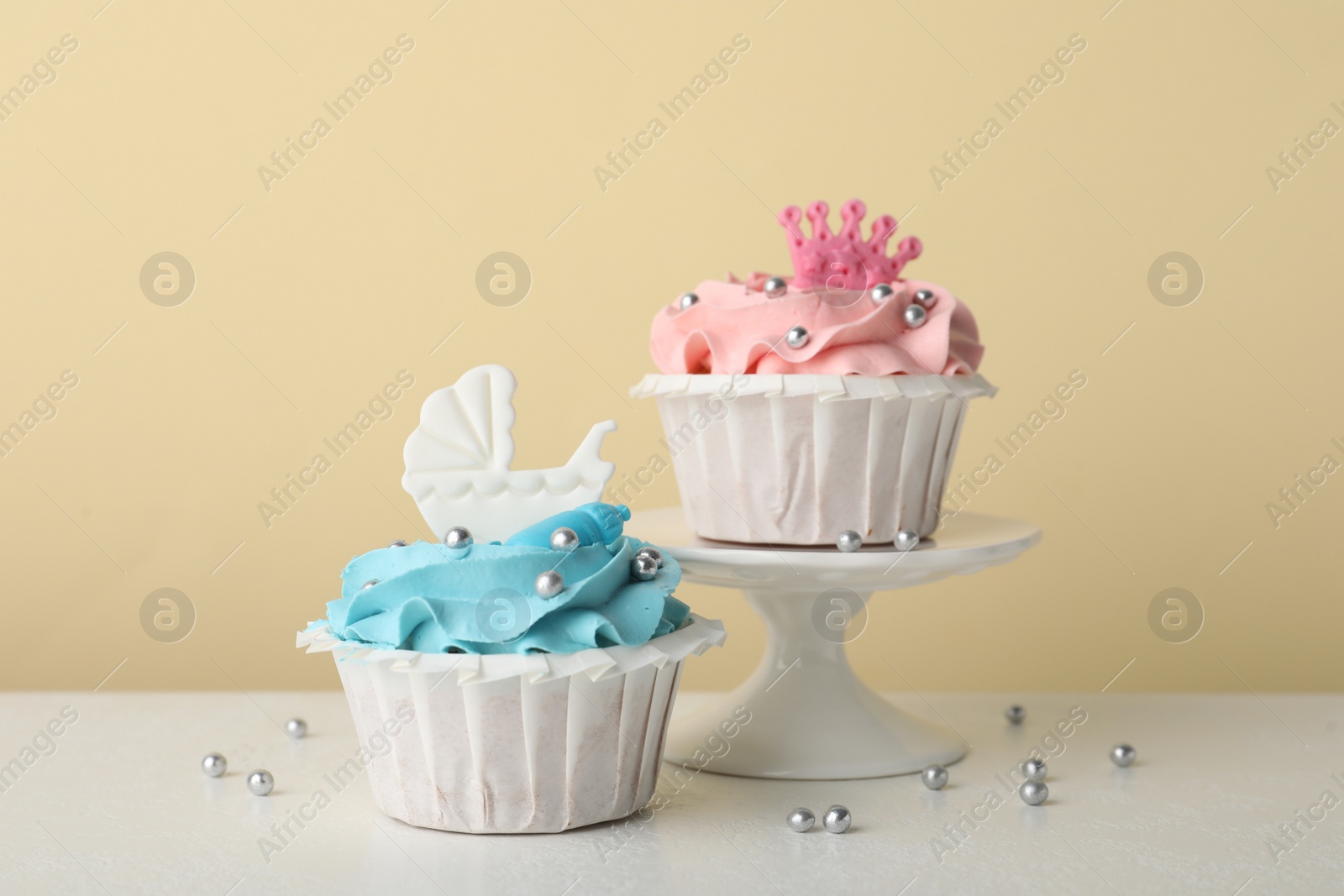 Photo of Delicious cupcakes with pink and light blue cream for baby shower on white table