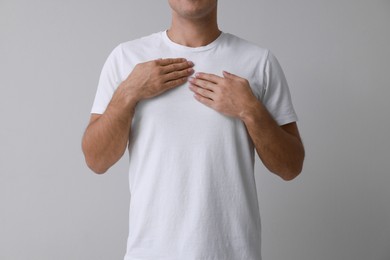 Photo of Man holding hands near chest on grey background, closeup