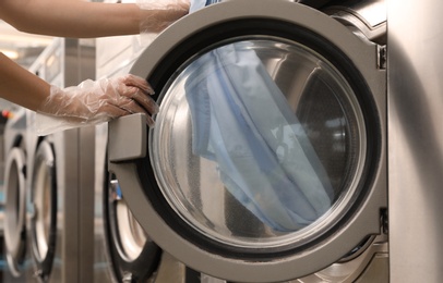 Photo of Young woman unloading washing machine in dry-cleaning, closeup