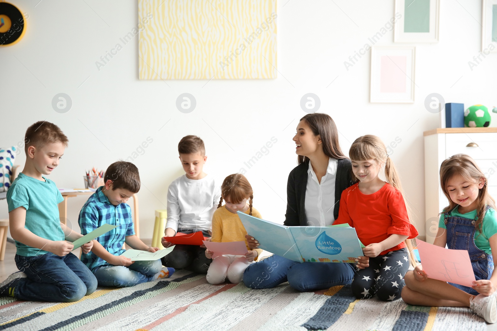 Photo of Cute little children with teacher in classroom at school