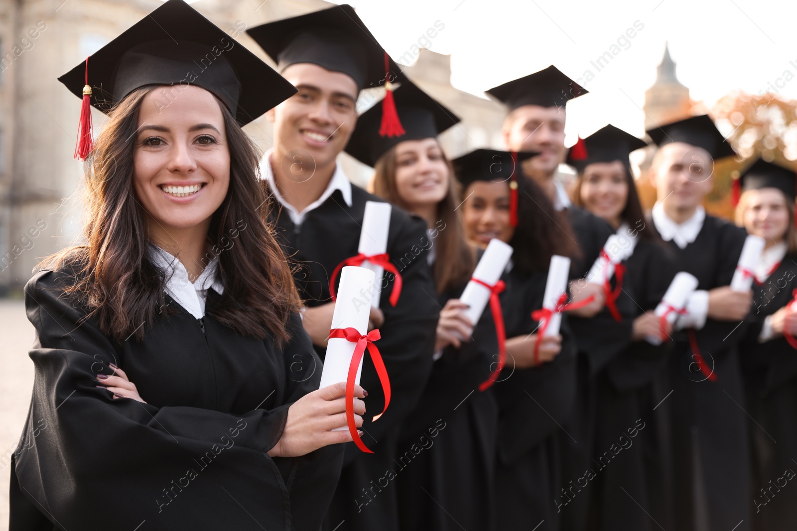 Photo of Happy students with diplomas outdoors. Graduation ceremony