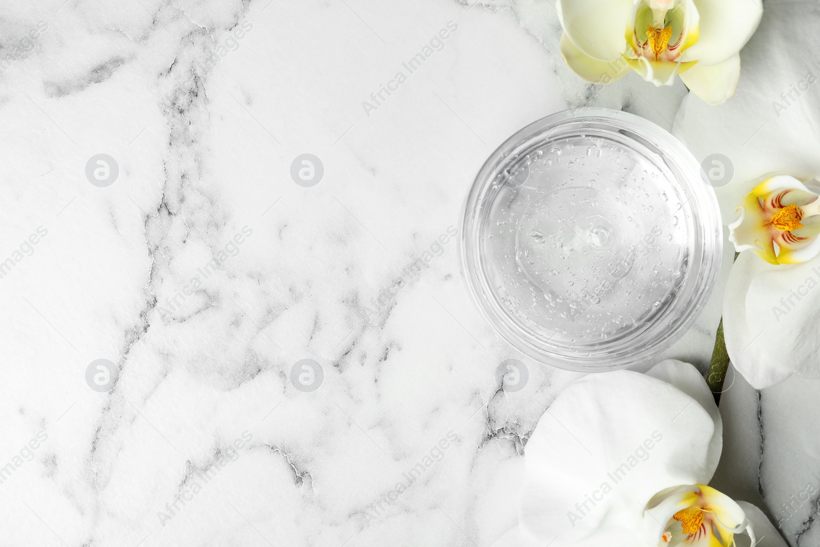 Photo of Flat lay composition with cosmetic gel and beautiful flowers on white marble table. Space for text