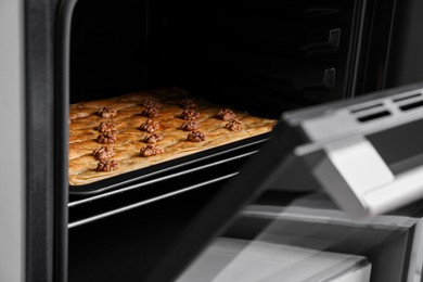 Photo of Baking pan of delicious baklava with walnuts in oven