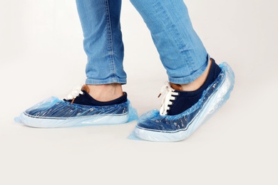 Photo of Man with blue shoe covers worn over sneakers on white background, closeup