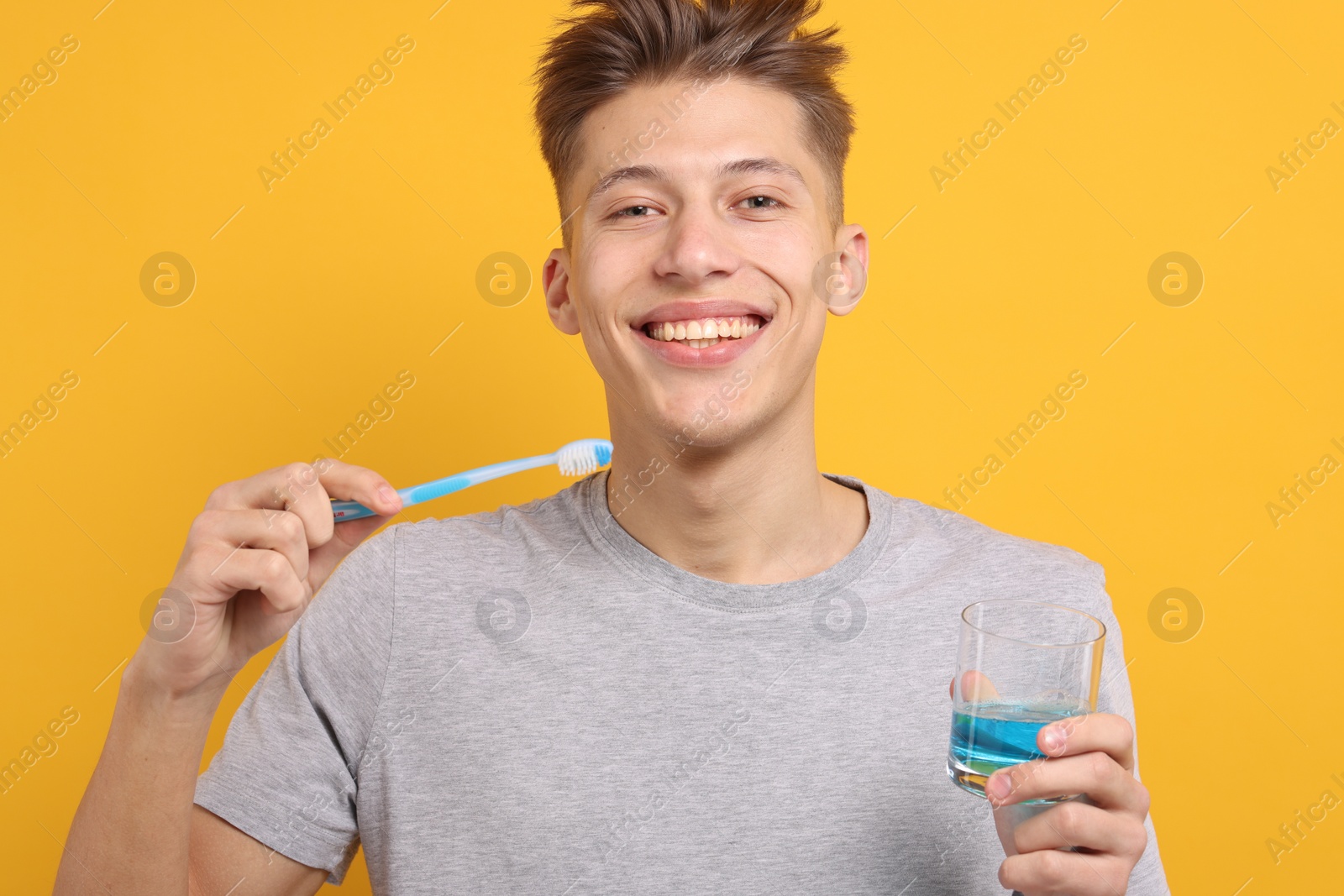 Photo of Young man with mouthwash and toothbrush on yellow background