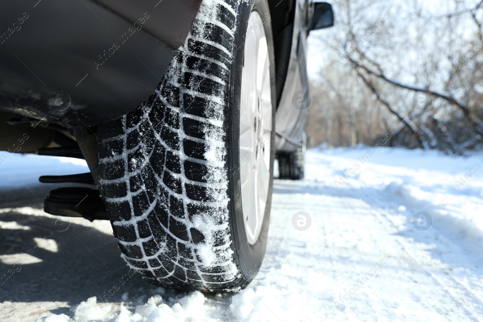 Photo of Car with winter tires on snowy road, closeup view. Space for text