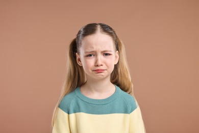 Photo of Portrait of sad girl on light brown background