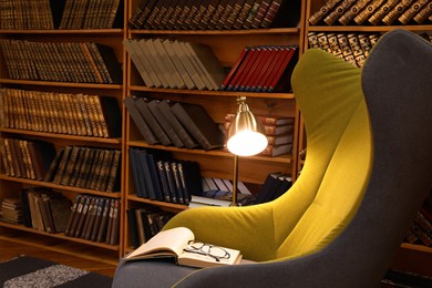Comfortable armchair with book and glasses in cozy home library
