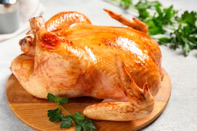 Photo of Tasty roasted chicken with parsley on light grey table