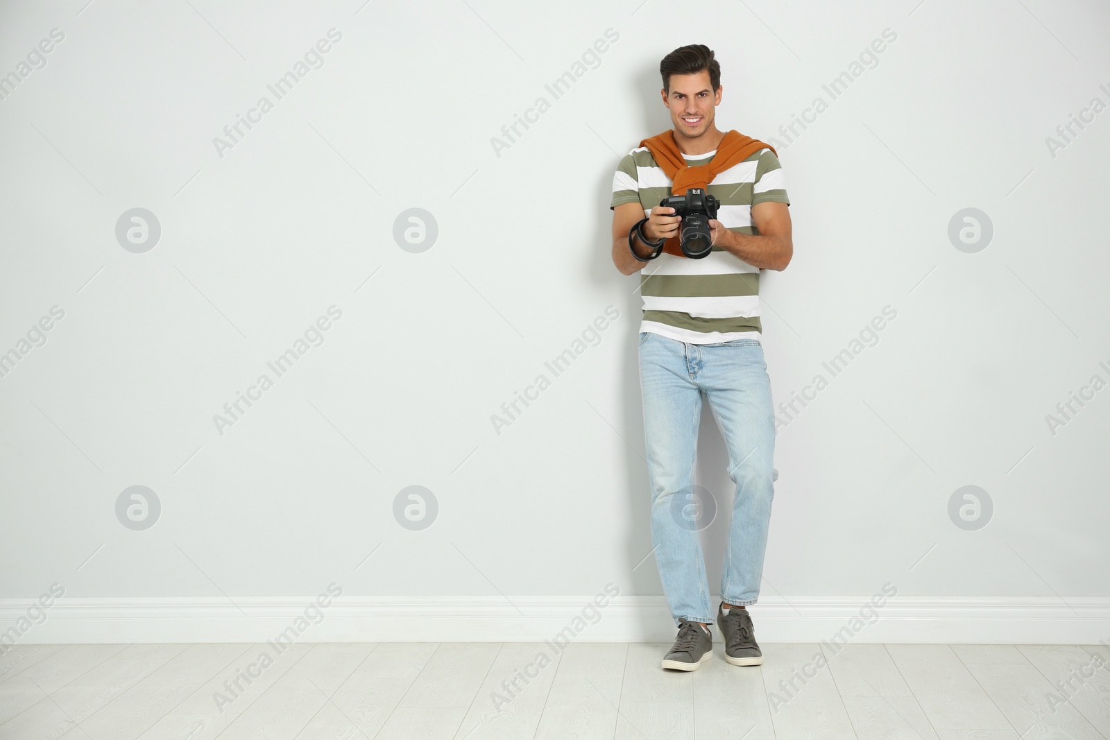 Photo of Professional photographer working near white wall in studio. Space for text