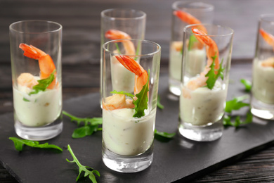 Photo of Delicious shrimp cocktail with tartar sauce served on black wooden table