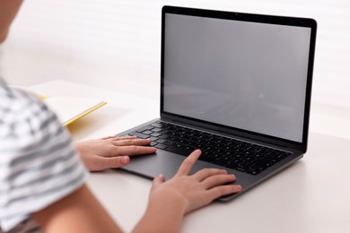 Photo of E-learning. Girl using laptop during online lesson at table indoors, closeup