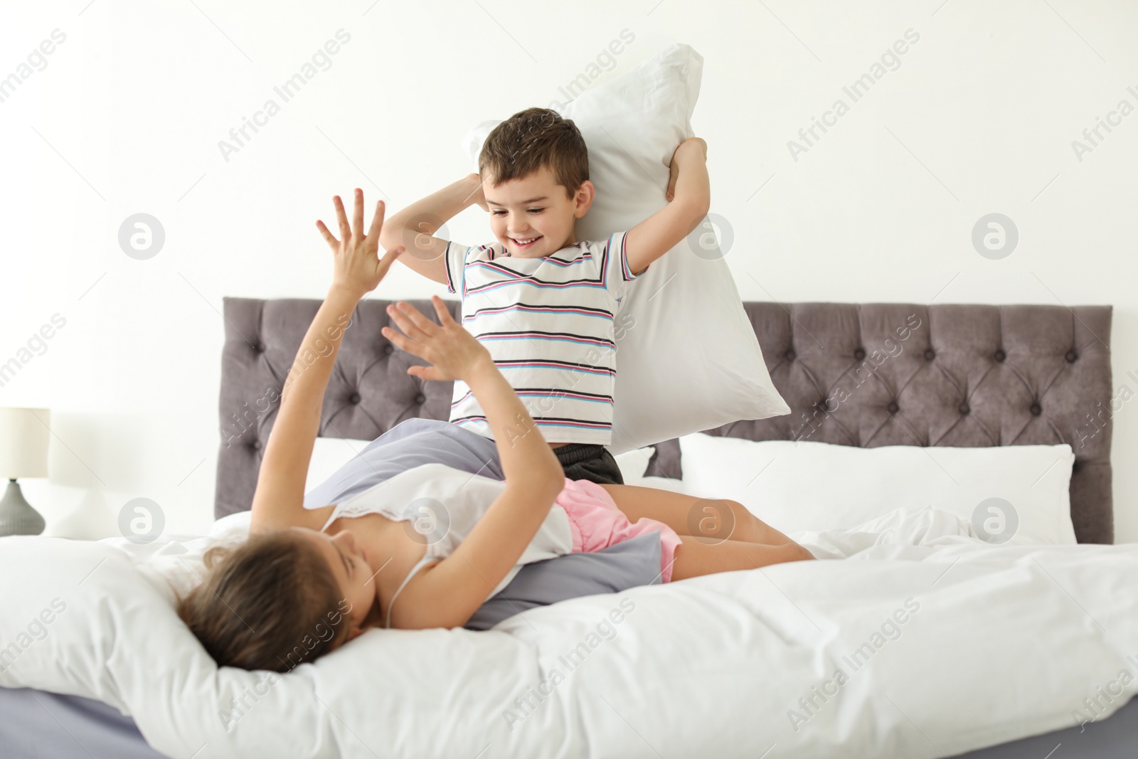 Photo of Happy children having pillow fight in bedroom