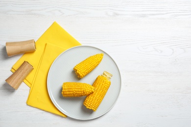 Photo of Flat lay composition with corn cobs on white wooden background. Space for text