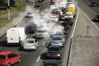 Image of Environmental pollution. Air contaminated with fumes in city. Cars surrounded by exhaust on road