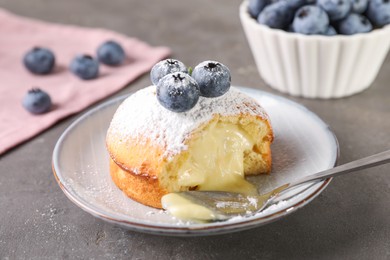 Photo of Tasty vanilla fondant with white chocolate and blueberries on grey table, closeup