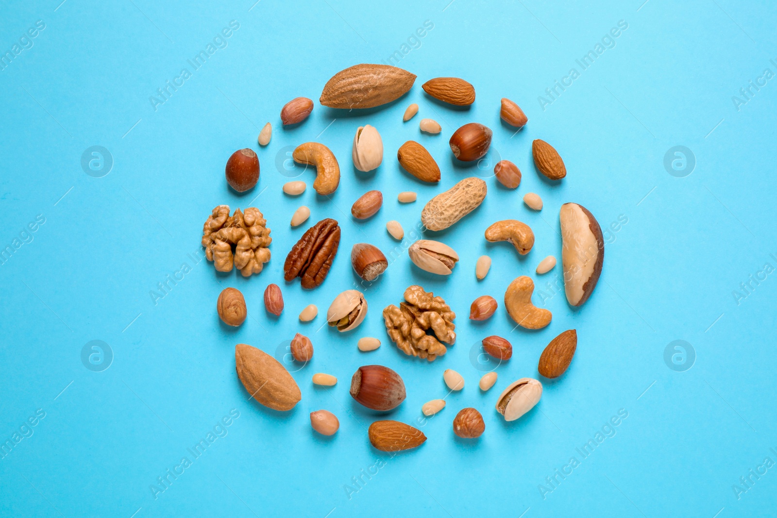 Photo of Different delicious nuts on light blue background, flat lay