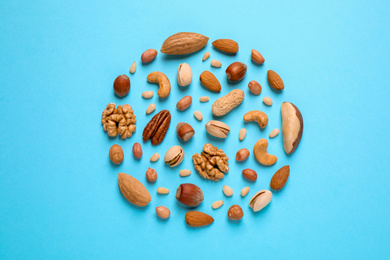 Different delicious nuts on light blue background, flat lay