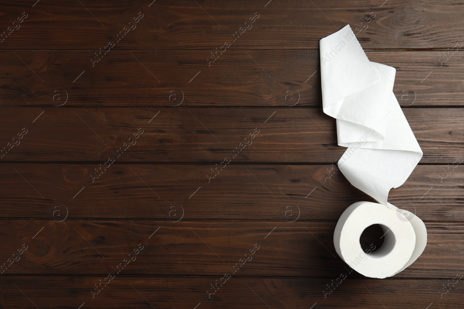 Photo of Toilet paper roll on wooden background, top view. Space for text