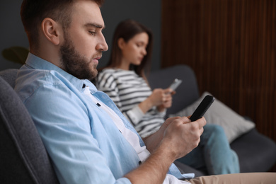 Couple addicted to smartphones ignoring each other at home. Relationship problems