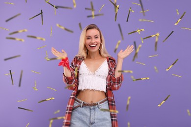 Happy woman and flying confetti on violet background