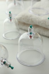 Photo of Plastic cups and towel on white marble table, closeup. Cupping therapy