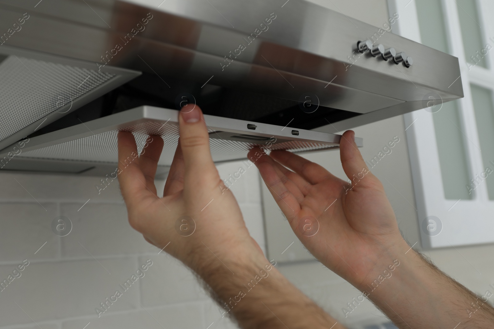 Photo of Worker repairing modern cooker hood indoors, closeup