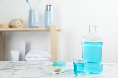 Photo of Mouthwash and other oral hygiene products on white marble table in bathroom, space for text