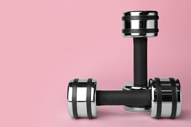 Photo of Two metal dumbbells on light pink background