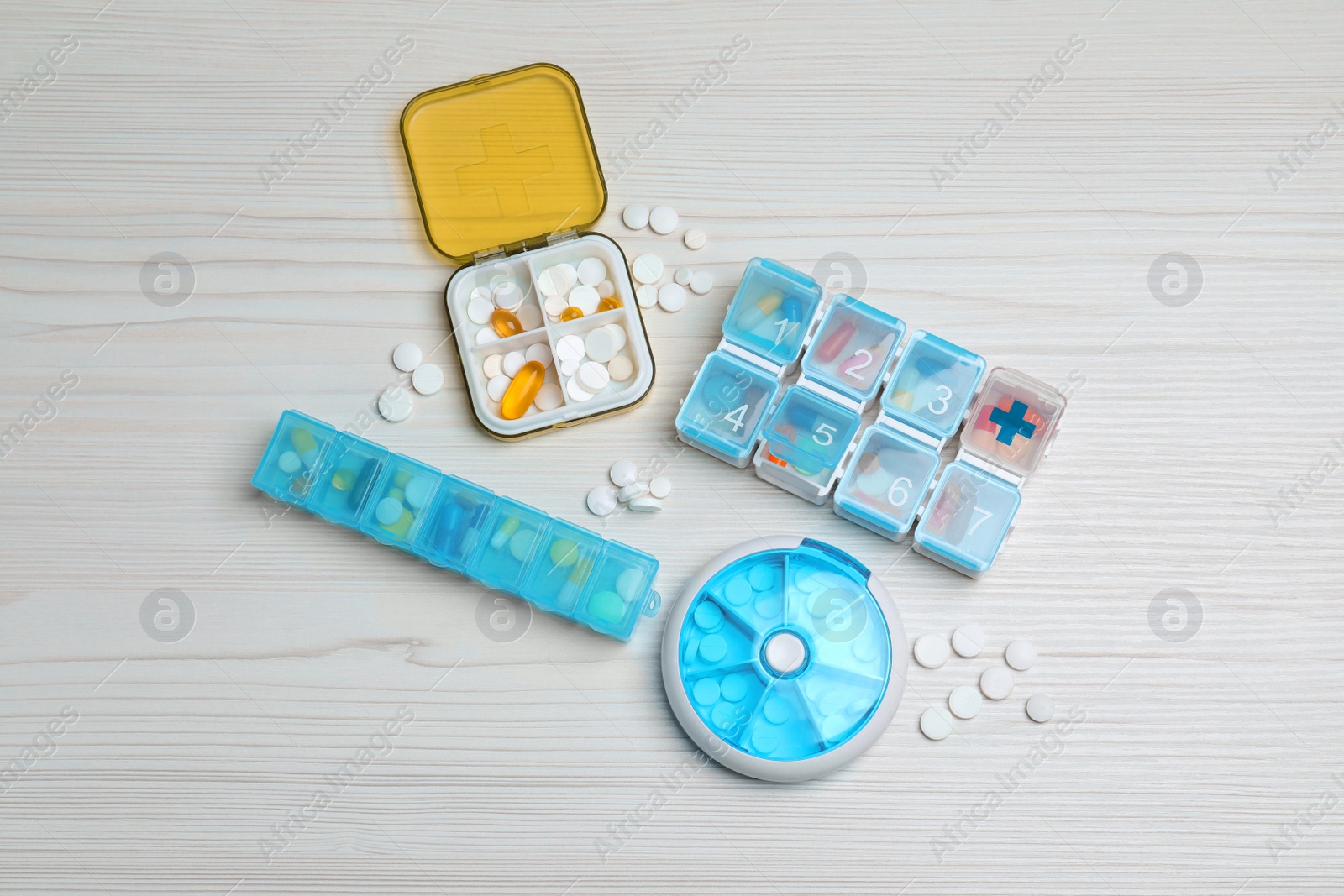 Photo of Pill boxes with medicaments on white wooden table, flat lay