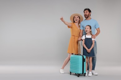 Photo of Happy family with turquoise suitcase on light grey background. Space for text