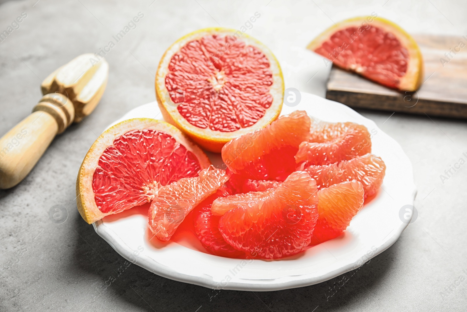 Photo of Plate with ripe grapefruit on grey background