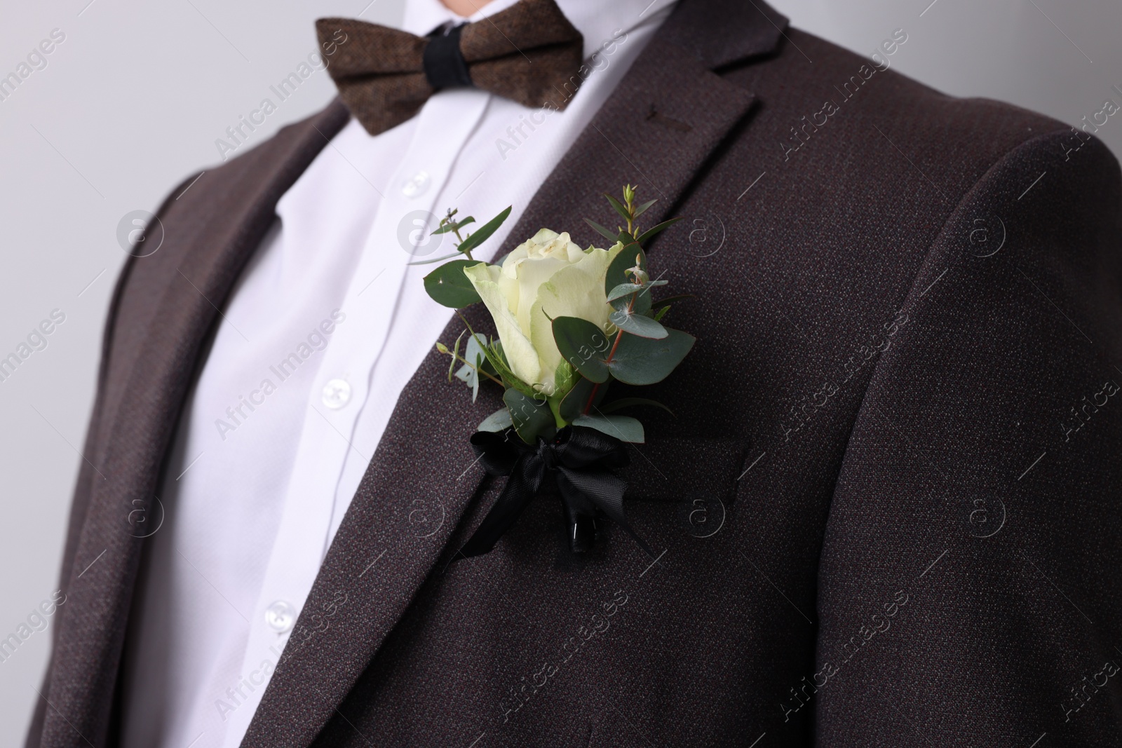 Photo of Groom with boutonniere on light grey background, closeup. Wedding accessory