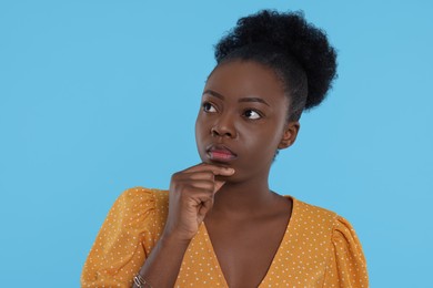 Portrait of concentrated young woman on light blue background