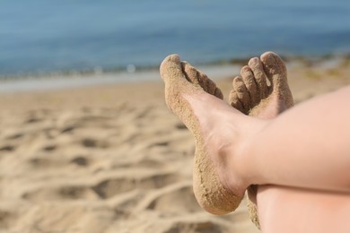 Photo of Woman resting on sand near sea, closeup of feet. Space for text