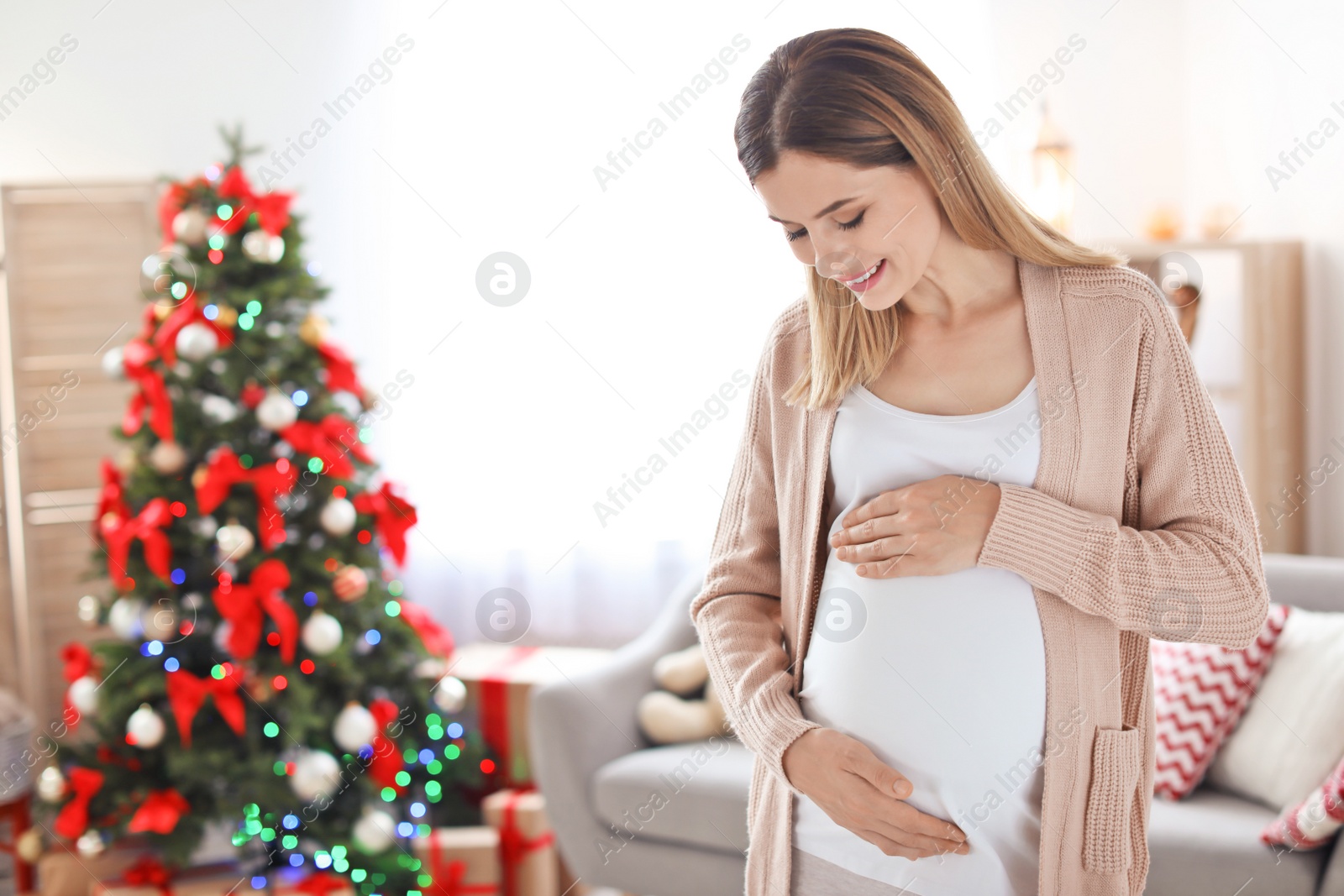 Photo of Happy pregnant woman in room decorated for Christmas