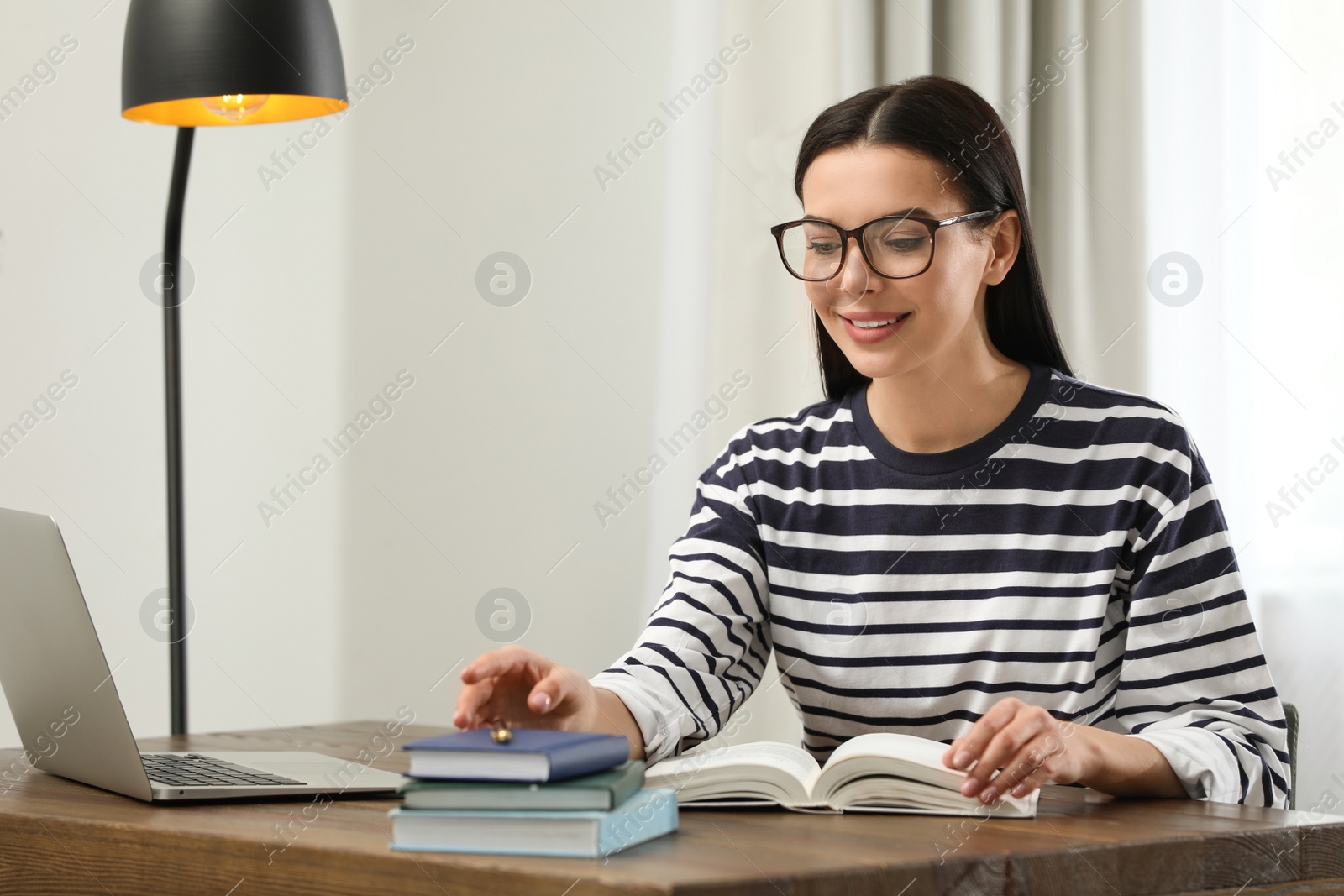 Photo of Young woman with laptop studying at table in library