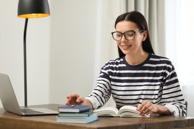 Young woman with laptop studying at table in library