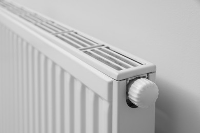Photo of Modern radiator on white wall, closeup. Central heating system
