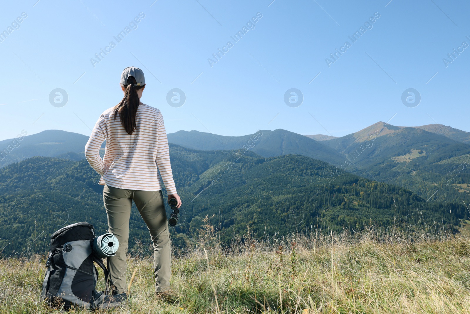 Photo of Tourist with hiking equipment and binoculars in mountains, back view