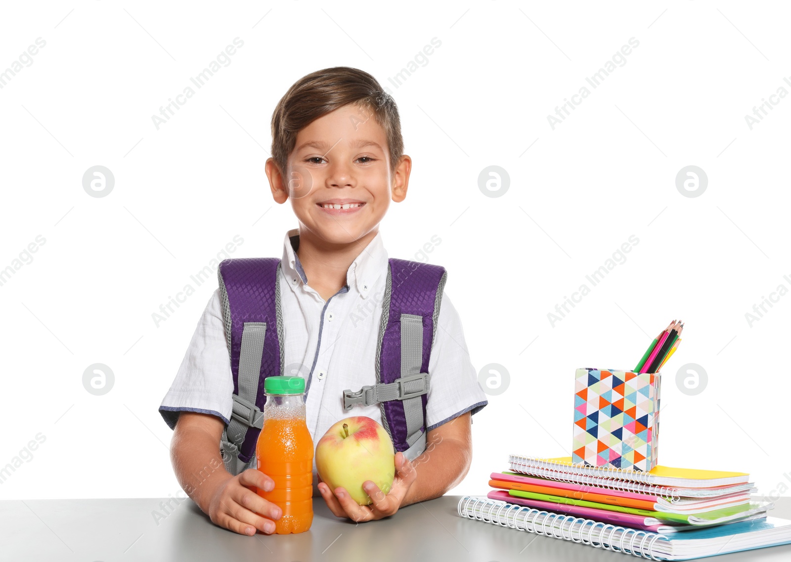 Photo of Schoolboy with healthy food and backpack sitting at table on white background