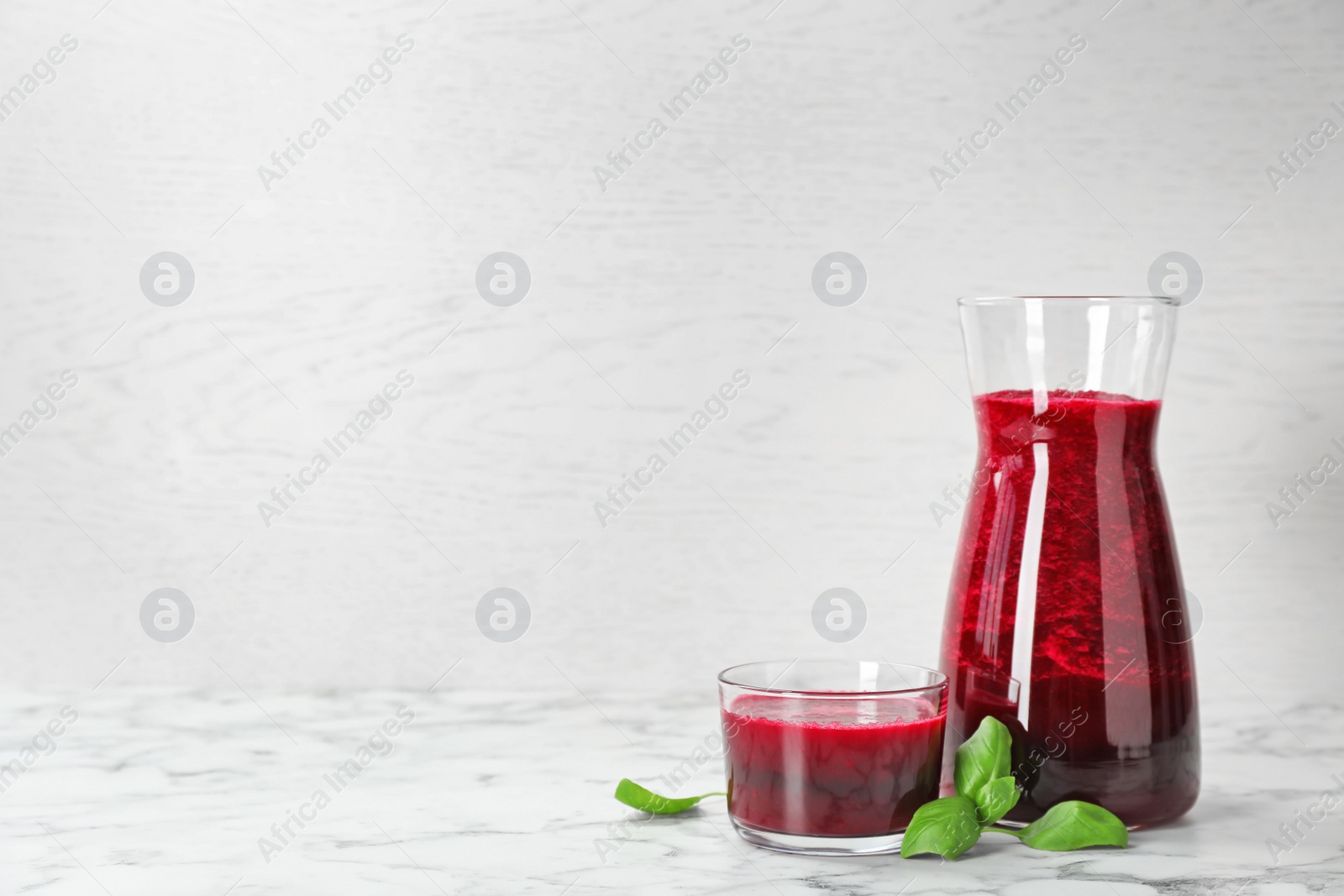 Photo of Jug and glass of fresh beet juice on table