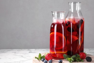 Delicious refreshing sangria and berries on white marble table, space for text