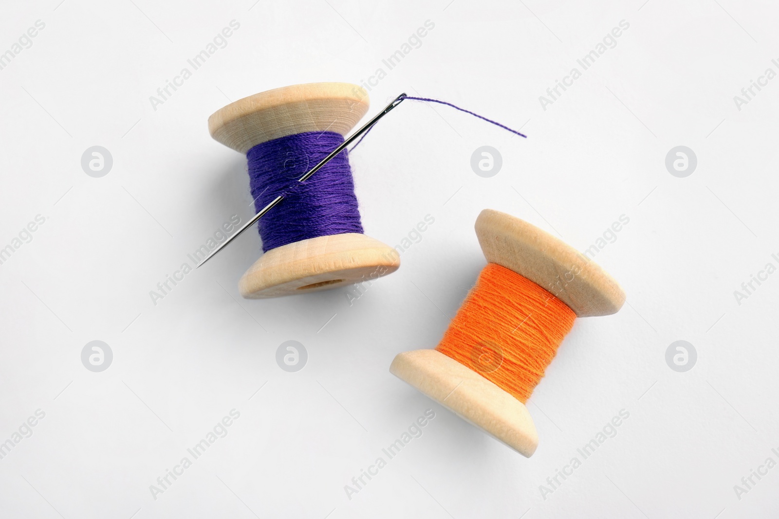 Photo of Colorful sewing threads with needle on white background, top view