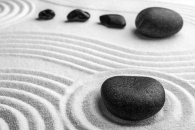 Photo of Black stones on sand with pattern. Zen, meditation, harmony