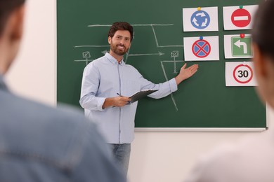 Photo of Teacher explaining traffic rules to audience during lesson in driving school