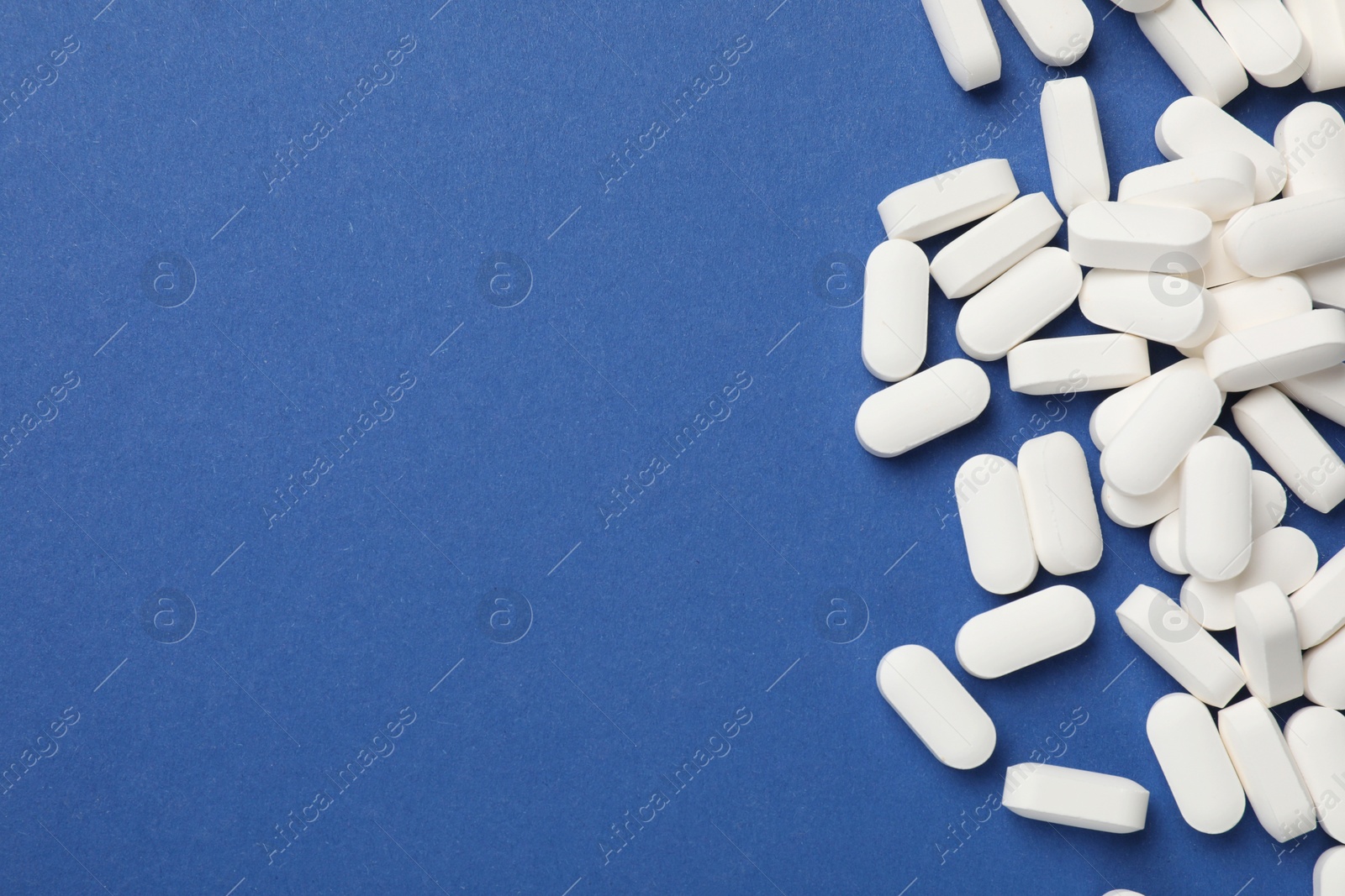 Photo of Vitamin pills on blue background, flat lay. Space for text